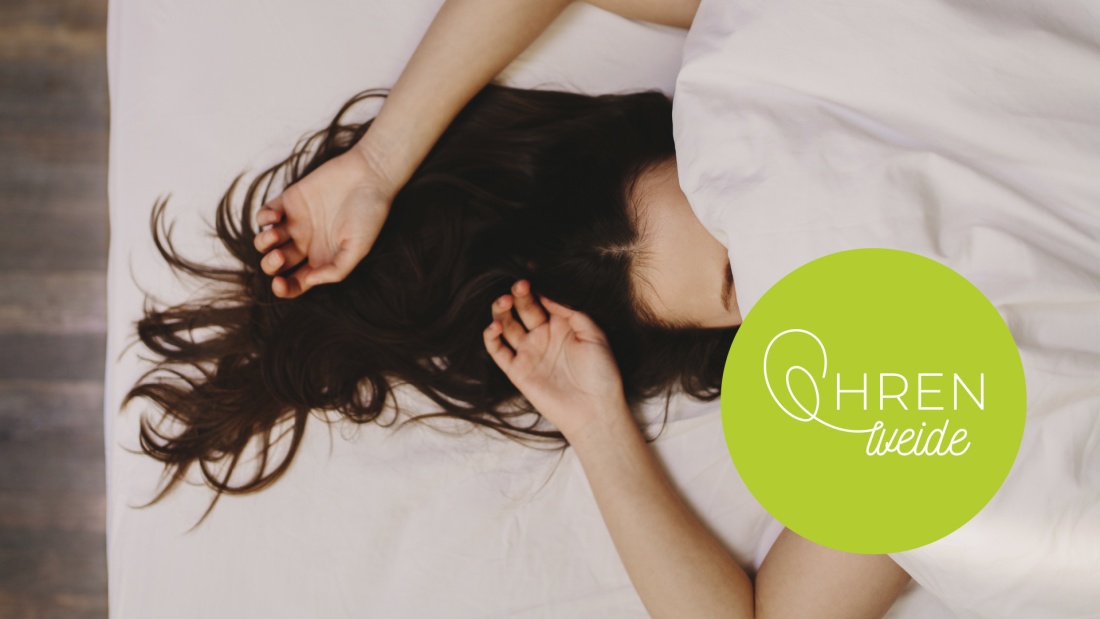 schlafende Frau mit ausgebreiteten Haaren auf weißem Bettlaken