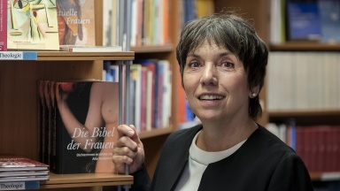 Margot Käßmann vor Bücherregal mit Bibel und theologischen Büchern