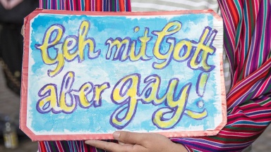 Schild "Geh mit Gott aber gay!" gegen Homophobie