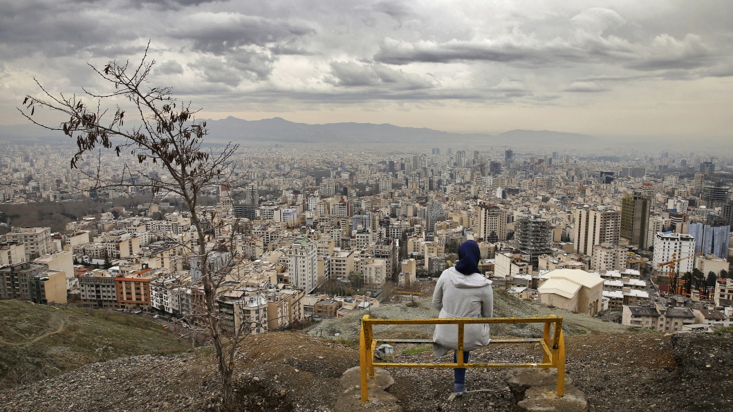 Eine Frau sitzt auf einer Bank auf der Aussichtsplattform vom Tochal Gebirge, mit Blick auf Teheran