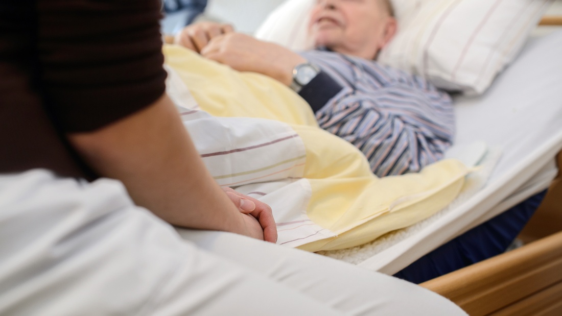Pflegekraft am Bett eine Gastes in einem deutschen Hospiz