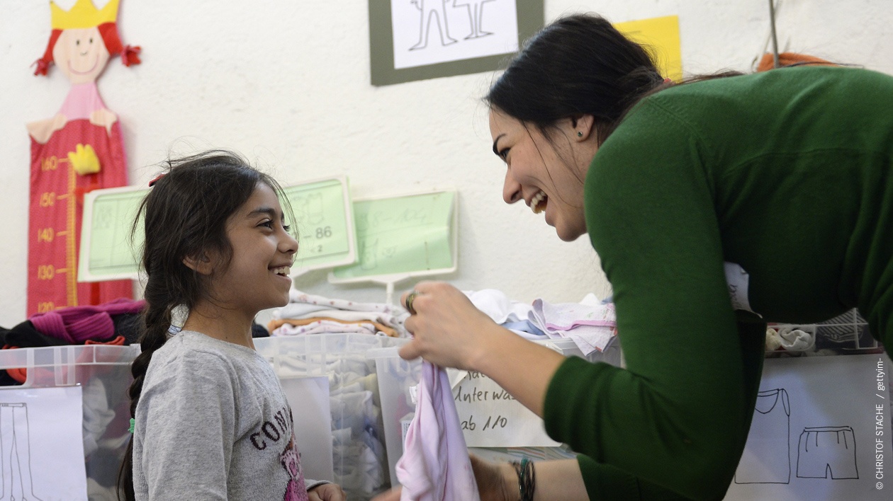 Ein Mädchen aus Syrien und eine Helferin in der Flüchtlingsunterkunft "Bayernkaserne" in München lachen sich an