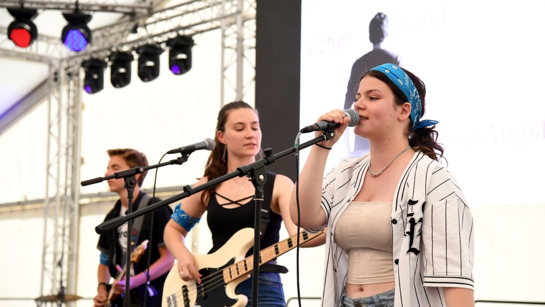 Frauenbandmitglieder auf der Bühne mit Gitarre und singend vor Mikrofon