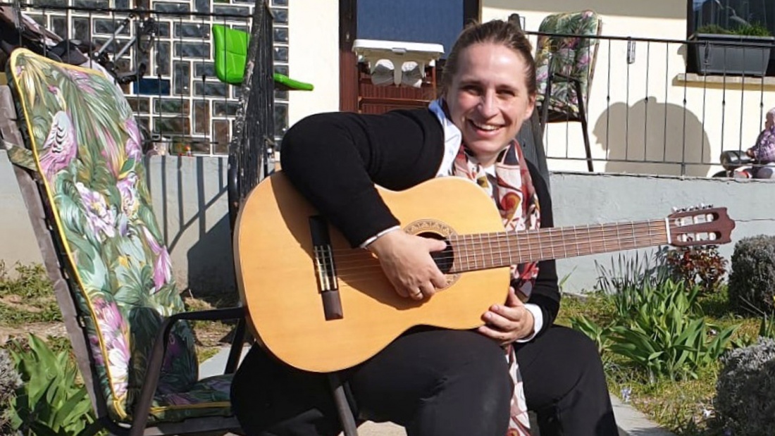 Die Pfarrerin Anneke Peereboom spielt Gitarre zur Corona-Miniandacht an der Tür.