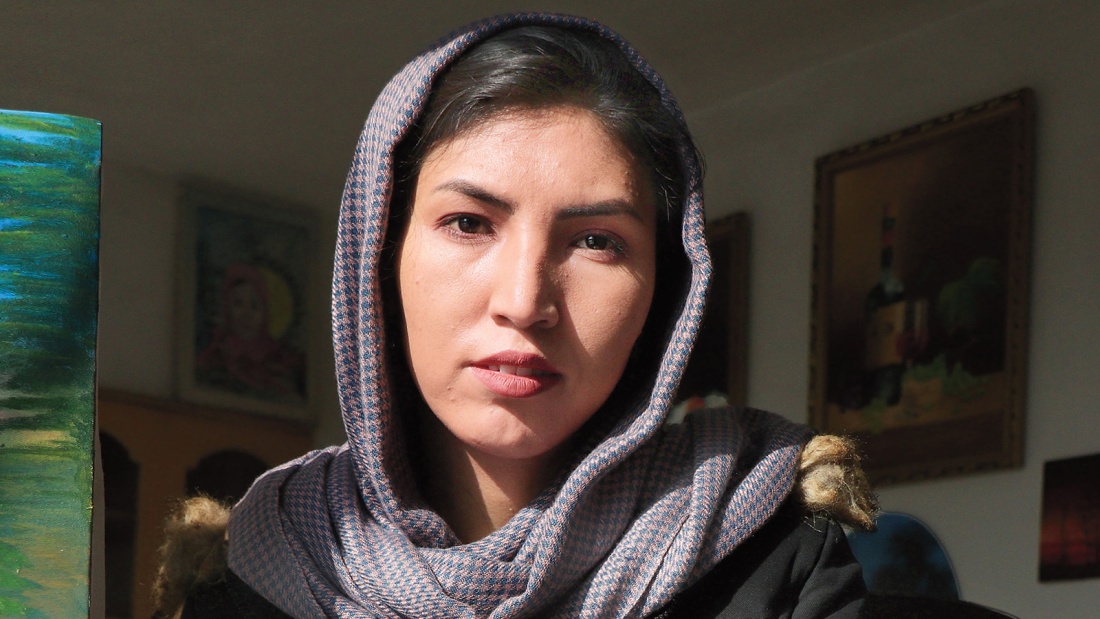 Eine junge afghanische Frau mit Schleier in einem Zimmer blickt in die Kamera