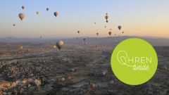 Heißluftballons fliegen über Landschaft bei Sonnenaufgang