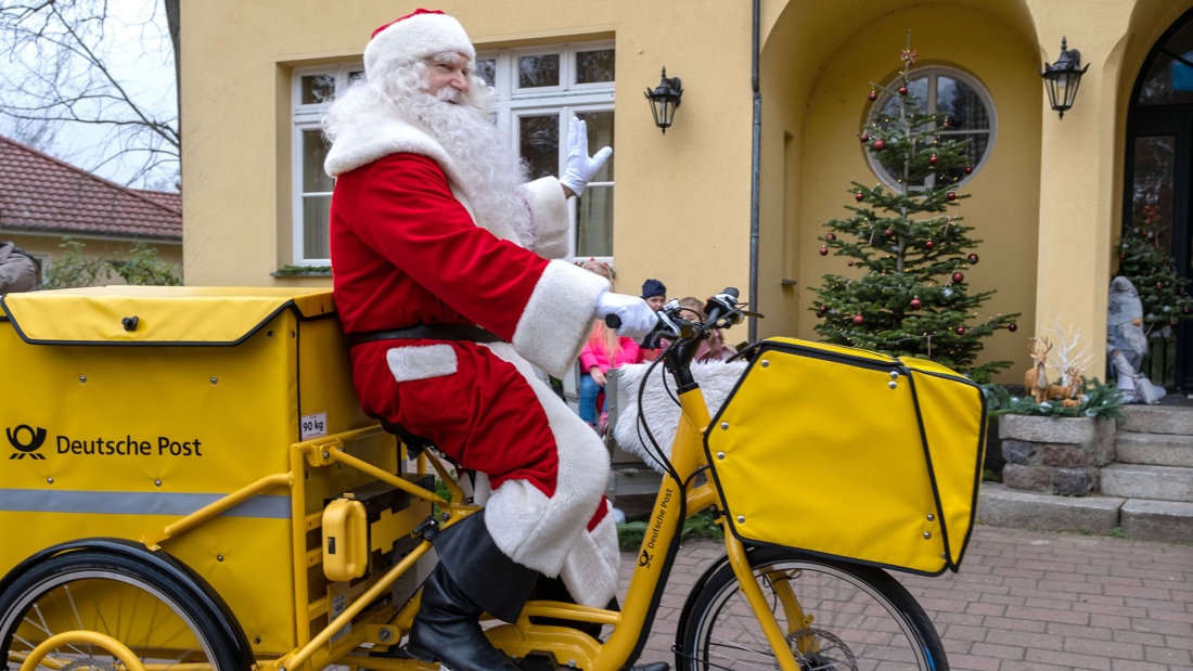 Weihnachtsmann auf umweltfreundlichem gelben Elektro-Dreirad