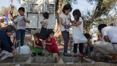Flüchtlinge waschen sich an einer Wasserstelle in einem provisorischen Lager nahe dem Flüchtlingslager Moria.