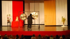 Blick auf eine Bühne mit zwei großen Gongs, auf denen eine Frau spielt.