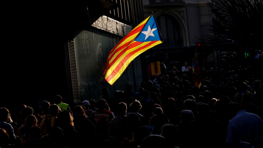 People walk through a street as an Estelada (Catalan separatist flag) flutters in Barcelona