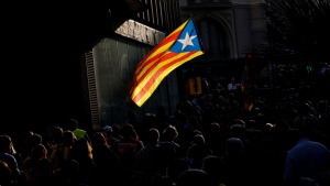 People walk through a street as an Estelada (Catalan separatist flag) flutters in Barcelona