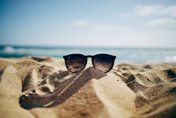 Sonnenbrille auf einem Strandhügel vor dem blauen Meer