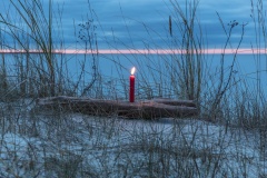 Eine einsame Kerze steht im Schnee und leuchtet