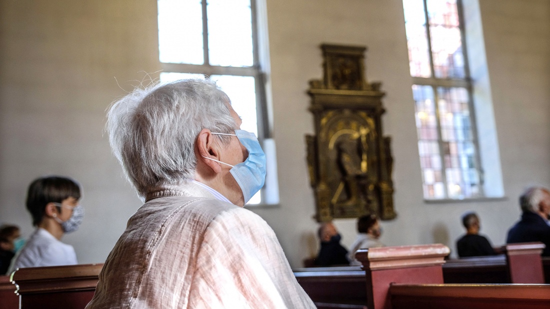 Gottesdienst in Zeiten der Corona-Pandemie: Menschen sitzen mit Masken und auf Abstand auf den Kirchenbänken