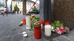 Kerzen und Blumen liegen vor einem geschlossenen und abgesperrten Geschäft in der Würzburger Innenstadt.