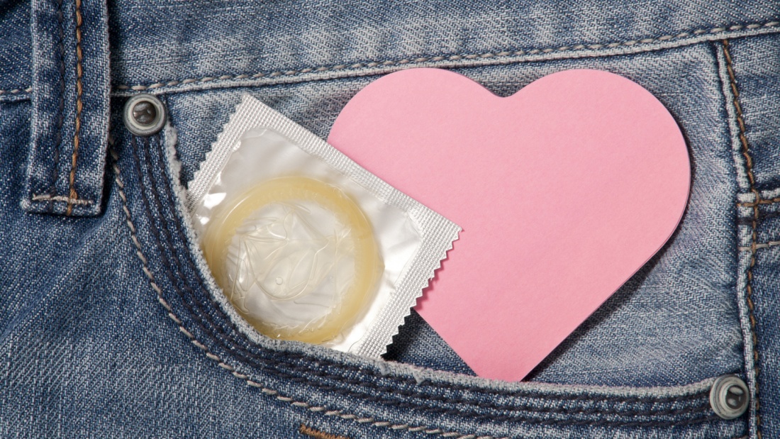 Symbolfoto für Aufklärung, Ausschnitt einer Jeanstasche mit Herzzettel und Kondom