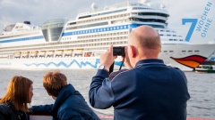 Ein Mann beobachtet durch ein Fernglas ein Kreuzfahrtschiff.