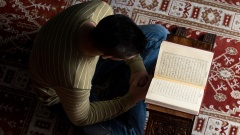 Ein Moslem sitzt auf dem Boden und liest in einem Koran.