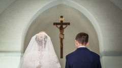 Brautpaar steht in der kirche vor einem Kruzifix.