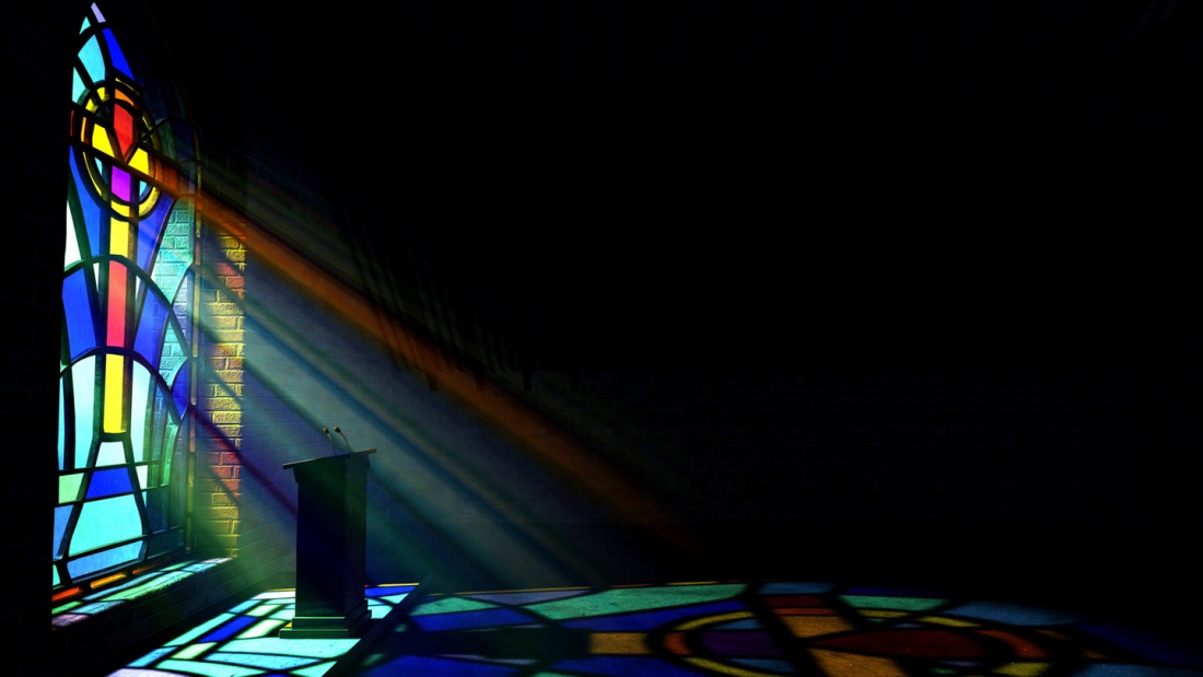 A dim old church interior lit by suns rays penetrating through a colorful stained glass window in the pattern of a crucifix reflecting colours on the floor and a speech pulpit
