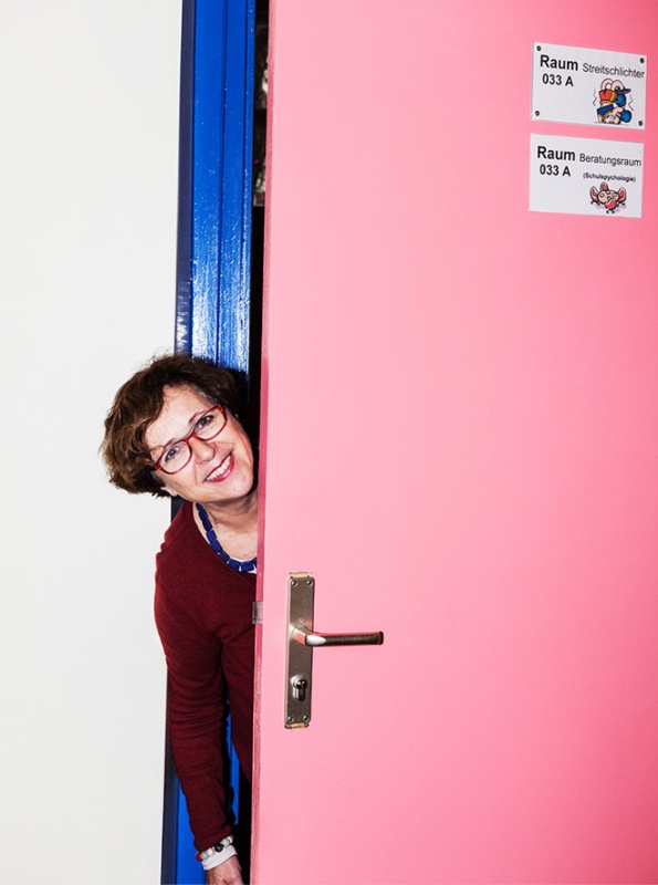 Frau Frank schaut durch rosa Tür