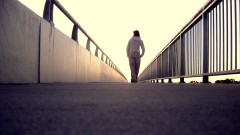 Junge Frau geht alleine über eine Brücke.