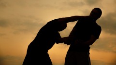 Silhouetten von zwei kämpfenden Männern bei Sonnenuntergang.