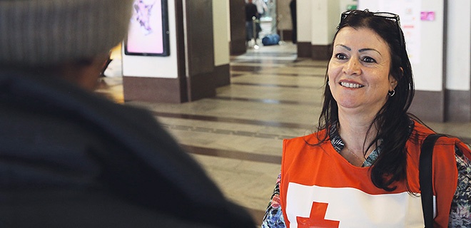 Eine Mitarbeiterin des Roten Kreuzes begrüßt am Stockholmer Bahnhof einen Flüchtling
