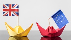 Papierschiffchen mit britischer Flagge und Papierschiffchen mit geknickter Europa-Flagge