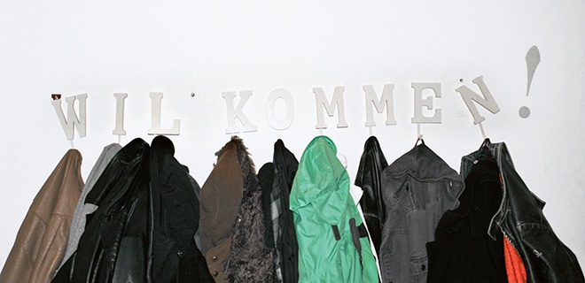 Jacken an einer Garderobe mit dem Schriftzug "Willkommen"