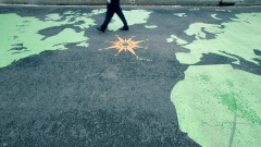Ein Mann läuft über eine auf den Boden gemalte Weltkarte.